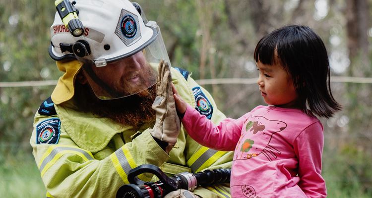 A firefighter gives a child a high five after using the hose